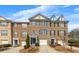 Inviting brick townhome with an attached garage, blue shutters, and manicured landscaping at 1868 Appaloosa Mill Ct, Buford, GA 30519