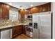 Well-lit kitchen with stainless steel appliances, dark cabinets, mosaic backsplash, and granite countertops at 265 Winding River Dr # G, Sandy Springs, GA 30350