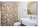The bathroom features a decorative shower curtain, a sink with storage, a vanity mirror, and modern fixtures throughout at 3290 Coachmans Ne Way, Roswell, GA 30075