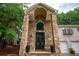 Grand stone entrance with arched doorway and double doors, complemented by a lush green lawn at 3290 Coachmans Ne Way, Roswell, GA 30075