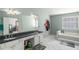 Luxurious bathroom with a double sink vanity, a soaking tub, white tile floors, and soft blue walls at 5035 Foxberry Ln, Roswell, GA 30075