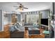 Cozy living room with hardwood floors, a ceiling fan, a large television, and comfortable seating at 5035 Foxberry Ln, Roswell, GA 30075