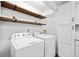 Bright laundry area features modern appliances, floating shelves, and sleek white cabinetry at 1379 Keys Lake Ne Dr, Brookhaven, GA 30319