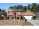 Two-story brick home with manicured bushes, black shutters, and a two-car attached garage at 3876 Elm Trace Ct, Loganville, GA 30052