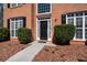 Close-up of a two-story brick home with a black front door, manicured bushes, and mulched flowerbeds at 3876 Elm Trace Ct, Loganville, GA 30052