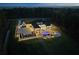 Aerial view of luxury home at dusk featuring extensive hardscape, landscape lighting and large backyard pool at 4100 Oak Hill Rd, Douglasville, GA 30135