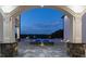 View from a columned archway framing a landscaped patio with a stunning pool and fire features; luxury at its finest at 4100 Oak Hill Rd, Douglasville, GA 30135