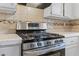 This kitchen features a stainless steel range, light cabinets, and neutral tile backsplash at 951 Orchard Mill Ln, Lawrenceville, GA 30043