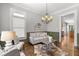 Cozy living room with a decorative chandelier, traditional trim, stylish seating, and hardwood floors at 1214 Oglethorpe Ne Ave, Brookhaven, GA 30319