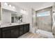 Bathroom featuring dual sinks, a large mirror, and a tiled shower with a window at 3166 Morris Hills Dr, Dacula, GA 30019