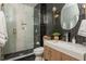 Modern bathroom featuring black and white tiling, glass shower, and wood vanity with white countertop at 4240 Agard St, Cumming, GA 30040