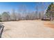 View of the expansive backyard with mature trees and a wood fence surround at 408 Hickory Fairway Ct, Woodstock, GA 30188