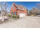 Side view of brick residence with attached three-car garage and lush greenery at 408 Hickory Fairway Ct, Woodstock, GA 30188
