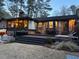 Inviting back exterior of brick home with spacious deck, outdoor seating, and warm interior lighting at 3504 Palace Ct, Tucker, GA 30084