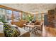 Bright sunroom with hardwood floors, brick accent wall and a wall of windows overlooking lush landscaping at 3504 Palace Ct, Tucker, GA 30084