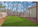 Backyard view of the side of home with green grass, wood fence, and mature trees at 511 Millwood Ct, Canton, GA 30114