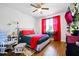 Well-lit bedroom with a ceiling fan, wood floors, and red accents at 555 Birkdale Dr, Fairburn, GA 30213