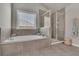 Gray tiled main bathroom featuring a glass shower, soaking tub, and big window providing natural light at 194 Lakestone Parkway, Woodstock, GA 30188