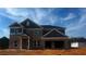 Two-story brick home featuring a two-car garage and covered front porch under a clear sky at 3191 Morris Hills Dr, Dacula, GA 30019
