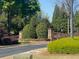 Landscaped community entrance with stone pillars, wooden fences, and mature trees for a welcoming feel at 441 Highlands Loop, Woodstock, GA 30188