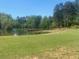 Scenic lake view with lush green lawn, mature trees, and a wooden dock at 441 Highlands Loop, Woodstock, GA 30188