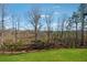 Spacious backyard featuring a lush green lawn, a black metal fence, and wooded views in the background at 7560 Wild Violet Dr, Cumming, GA 30040