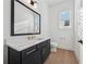 Chic powder room with black vanity, quartz countertop, modern gold hardware, and stylish mirror at 7560 Wild Violet Dr, Cumming, GA 30040