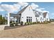 Front exterior of a modern white house with large windows, manicured landscaping, and a welcoming front porch at 7560 Wild Violet Dr, Cumming, GA 30040