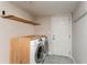 Convenient laundry room featuring modern, front-loading washer and dryer, light wood countertop and shelving, and a neutral color palette at 1613 Westwood Sw Ave, Atlanta, GA 30310