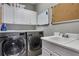 Well-equipped laundry room with modern washer and dryer, sink, and storage cabinets at 3493 Maryhill Nw Ln, Kennesaw, GA 30152