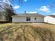 Back of home featuring a small concrete patio and a spacious grassy yard surrounded by mature trees at 10632 Pine Forest Ne Ln, Jonesboro, GA 30238