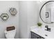 Stylish half bathroom featuring a round mirror, modern fixtures, and geometric wall decor at 503 Stanford Pl, Woodstock, GA 30188