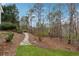 Backyard featuring a stone pathway, lush greenery, and mature trees at 5515 Punkintown Rd, Douglasville, GA 30135