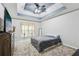 Bedroom featuring tray ceilings with ceiling fan, carpet floors, dresser, and light-blocking curtains at 960 Sugar Meadow Dr, Sugar Hill, GA 30518