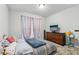 Cozy bedroom featuring carpet floors, a window with rainbow curtains, and a dark wood dresser with a TV at 960 Sugar Meadow Dr, Sugar Hill, GA 30518