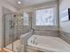 Bright bathroom showcasing a tiled glass shower, soaking tub, and large window for natural light at 1431 Torrington Dr, Auburn, GA 30011