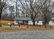 Charming single-story white brick home with black trim, a cozy front porch, and mature trees in the yard at 3250 Lee Dr, Buford, GA 30518