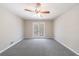 This bedroom features neutral paint, a ceiling fan, carpet floors, and french doors that lead to an outdoor space at 1618 Cheryl Leigh Dr, Riverdale, GA 30296