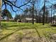An expansive lawn and mature trees comprise the backyard of this tan home with deck at 2087 Blackberry Ln, Auburn, GA 30011