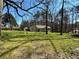 This home features a large, grassy backyard with mature trees, a wooden deck, and full fencing at 2087 Blackberry Ln, Auburn, GA 30011