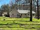 Tan colored home featuring a deck, and a spacious green lawn with mature trees at 2087 Blackberry Ln, Auburn, GA 30011