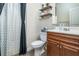 Cozy bathroom with wooden vanity, shelves, and shower with curtain at 784 Sunset Down Ct, Loganville, GA 30052