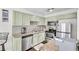 Well-lit kitchen featuring stainless steel appliances, granite countertops, and light green cabinetry at 6730 Gallant Se Ct, Mableton, GA 30126