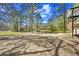 Large, cleared backyard with mature trees and partial view of the home and wooden deck at 6971 Tan Bark Ct, Riverdale, GA 30296