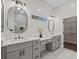 Bathroom featuring dual vanity with modern fixtures, sleek mirrors, and white tile floor at 6971 Tan Bark Ct, Riverdale, GA 30296