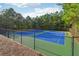 Community tennis court surrounded by mature trees and a black fence at 1624 River Main Ct, Lawrenceville, GA 30046