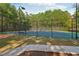 Community tennis court surrounded by mature trees and black fence at 1624 River Main Ct, Lawrenceville, GA 30046