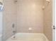 Neutral-tiled bathtub featuring chrome fixtures and shower head, offering a simple and clean bathing space at 5470 Beaver Ridge Dr, Cumming, GA 30040