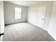 A clean, carpeted bedroom with a window allowing natural light and a door leading to other parts of the home at 5518 Legacy Trl, Douglasville, GA 30135