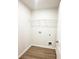 A simple laundry room area with connections and shelf for storage, featuring a wood-look floor at 5518 Legacy Trl, Douglasville, GA 30135